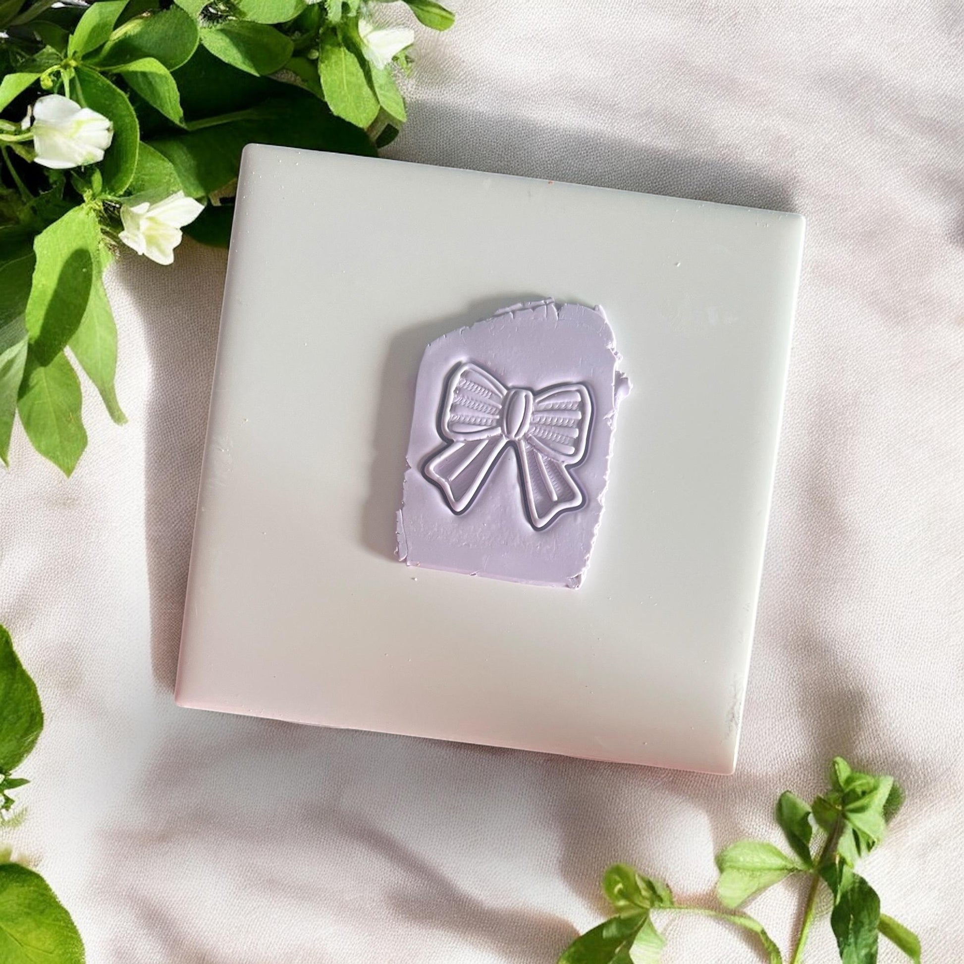 bow-shaped clay cutter pressed into lilac clay slab