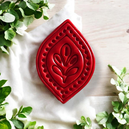 Red clay earring piece shaped with detailed petal drop mold