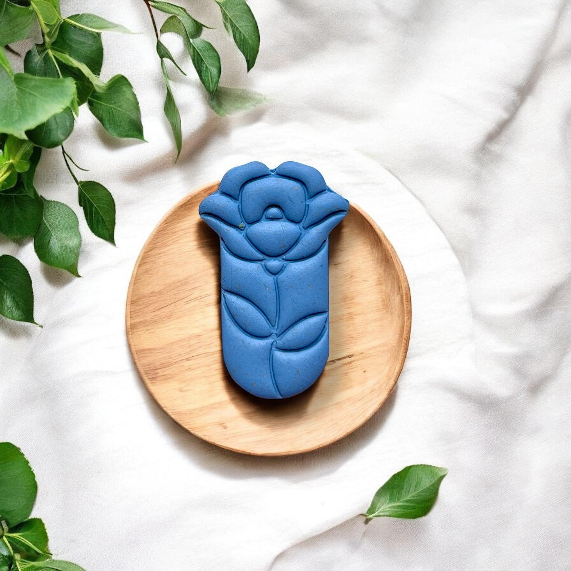 Finished blue teardrop flower clay piece on wood plate
