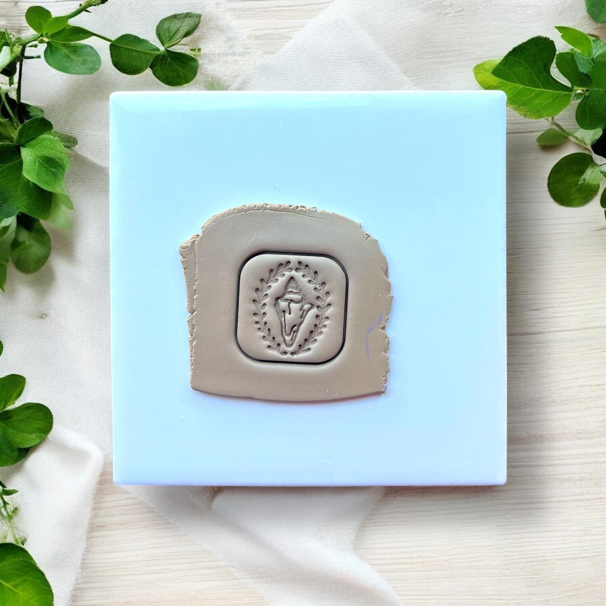 clay slab with shell design framed by leaves
