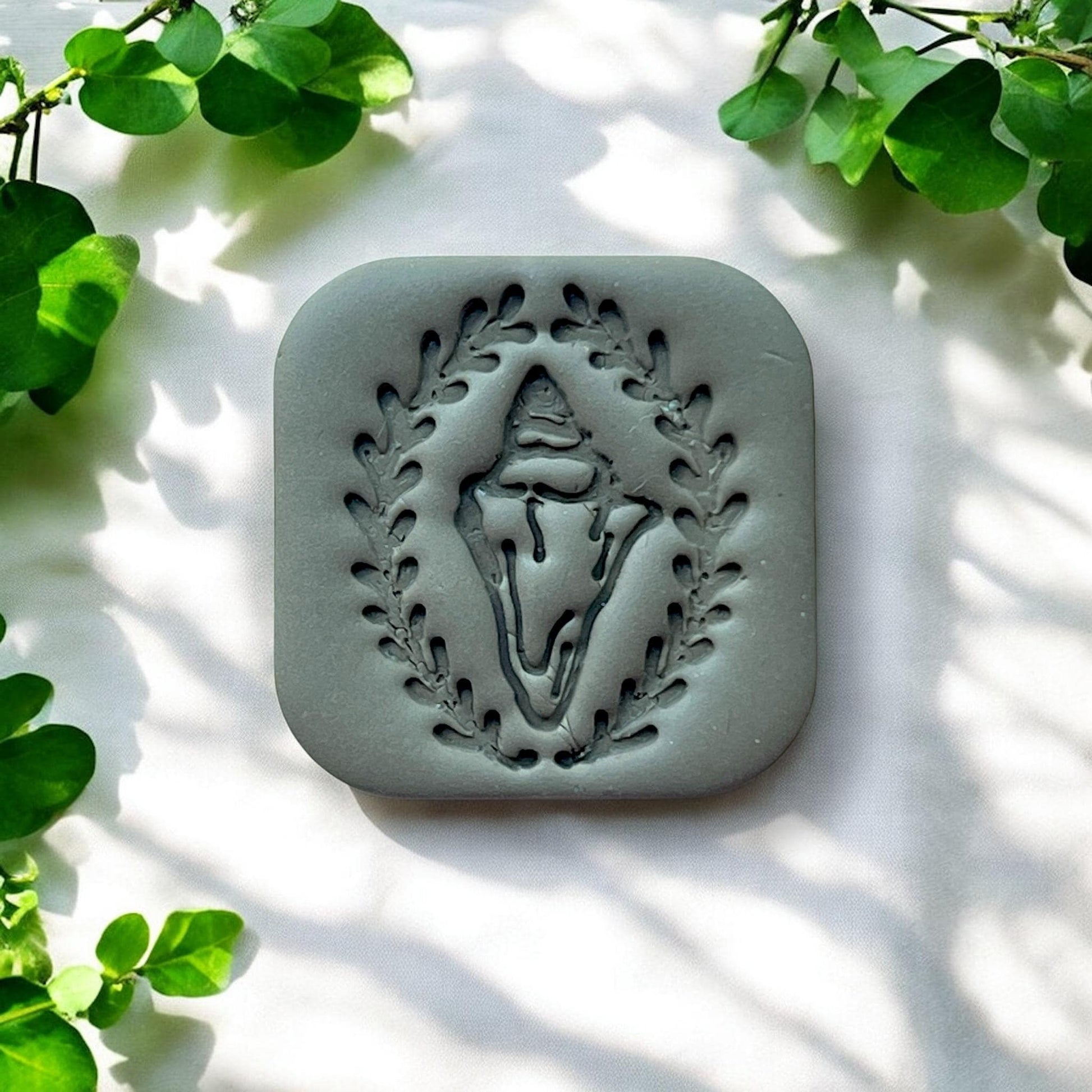 gray clay charm with shell and wreath-style frame