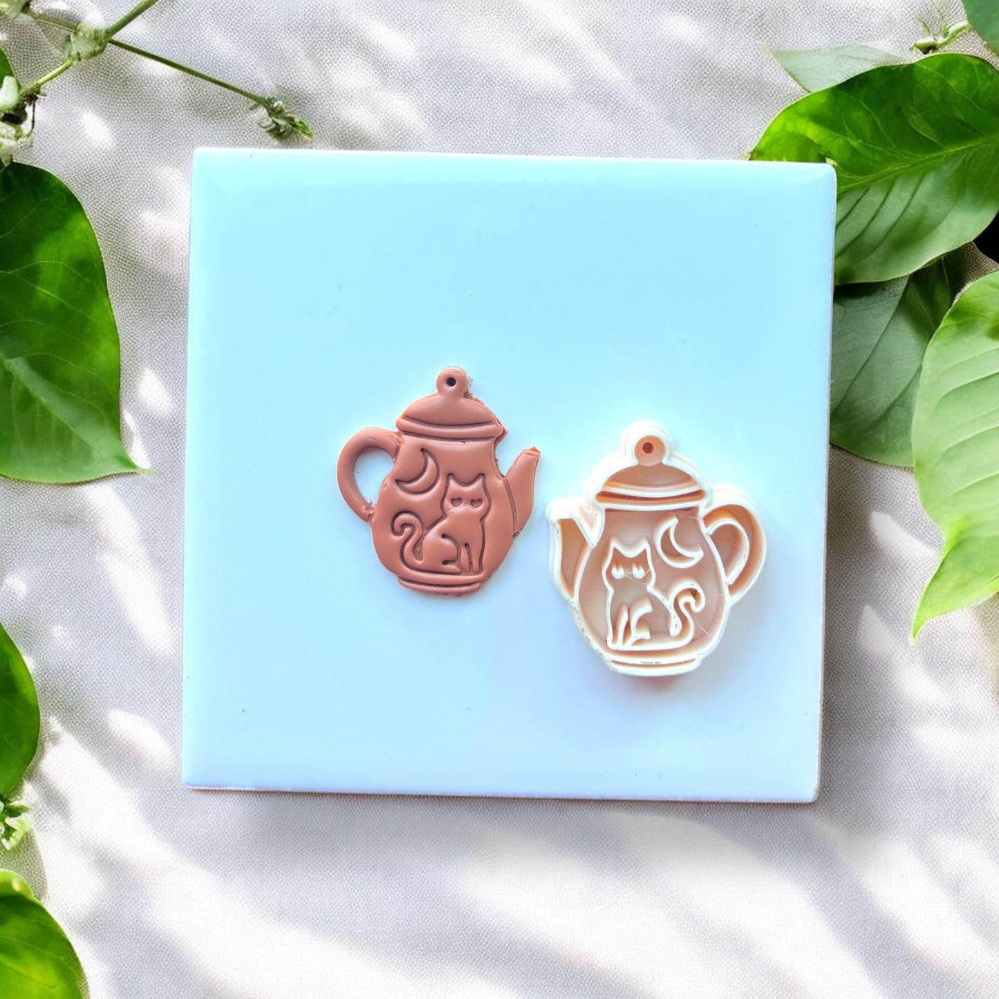 cat teapot charm beside matching clay cutter