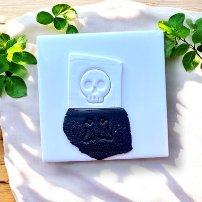 white clay slab with skull impression and black slab with boots