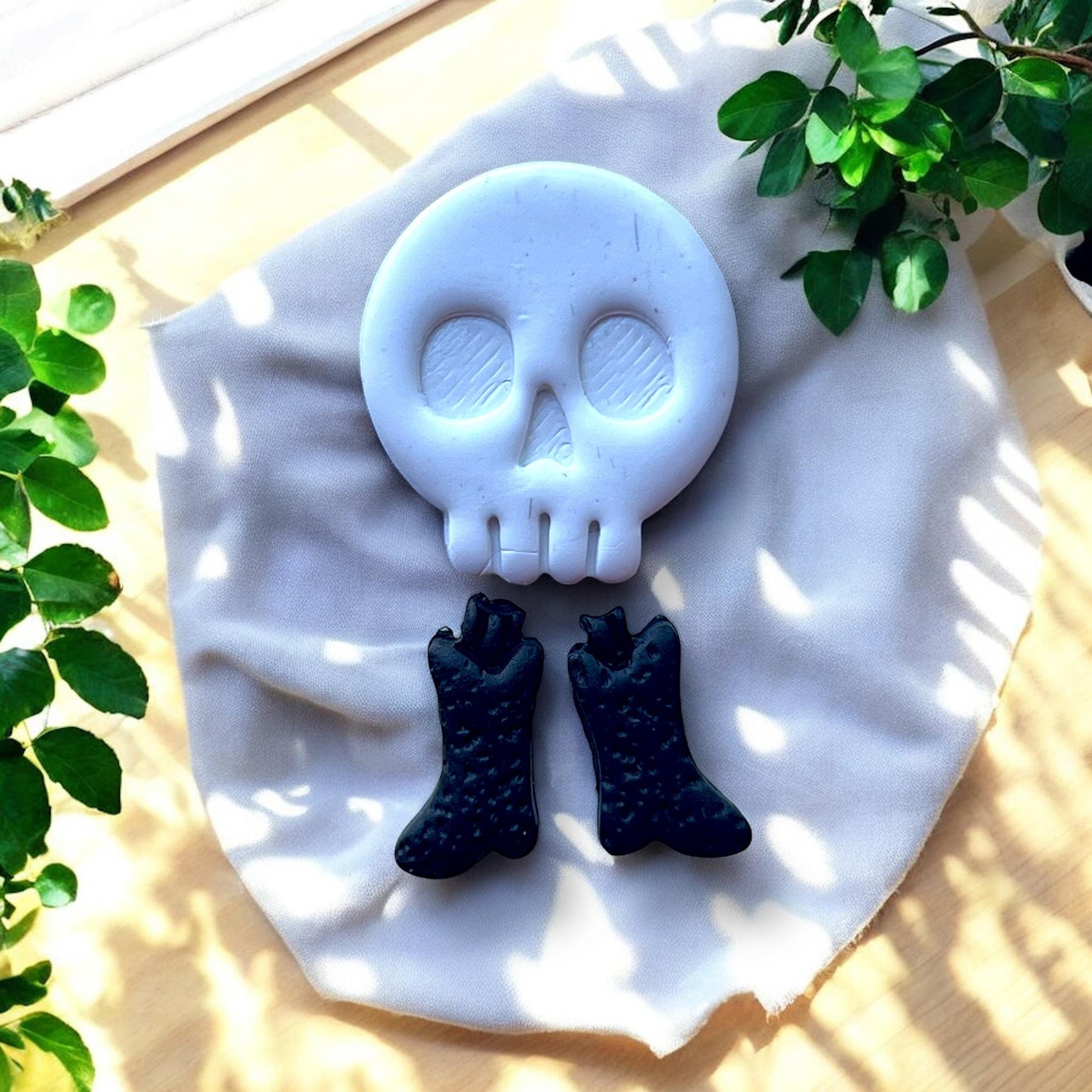 white skull charm with black boot charms laid on cloth