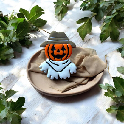 Finished multicolor pumpkin ghost cowboy earring displayed on a plate