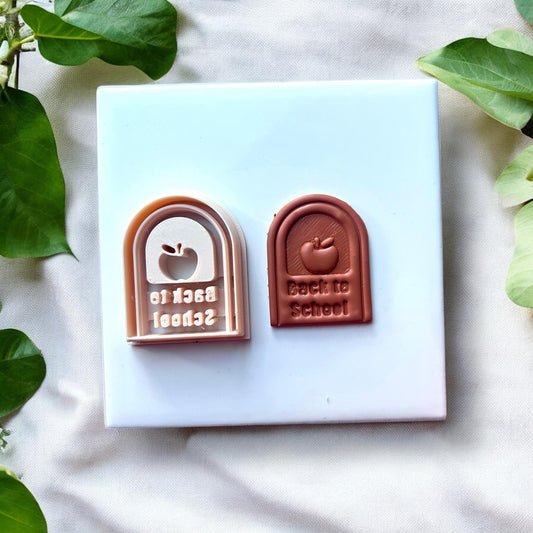 Polymer clay cutter next to finished clay piece with apple and arch