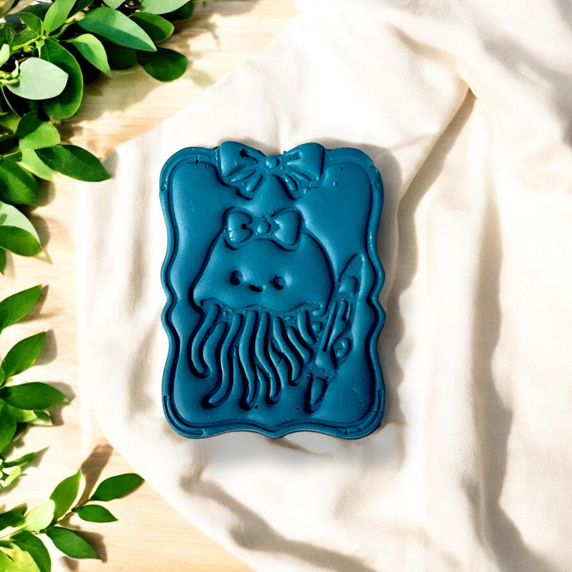 Finished jellyfish design on clay slab, surrounded by leaves