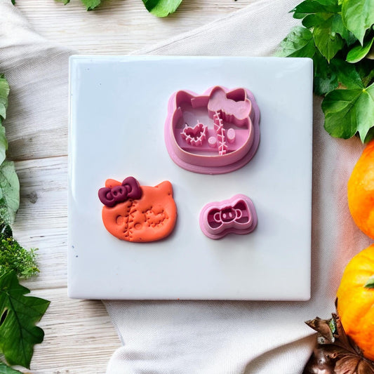Polymer clay cat head earring next to matching cutters