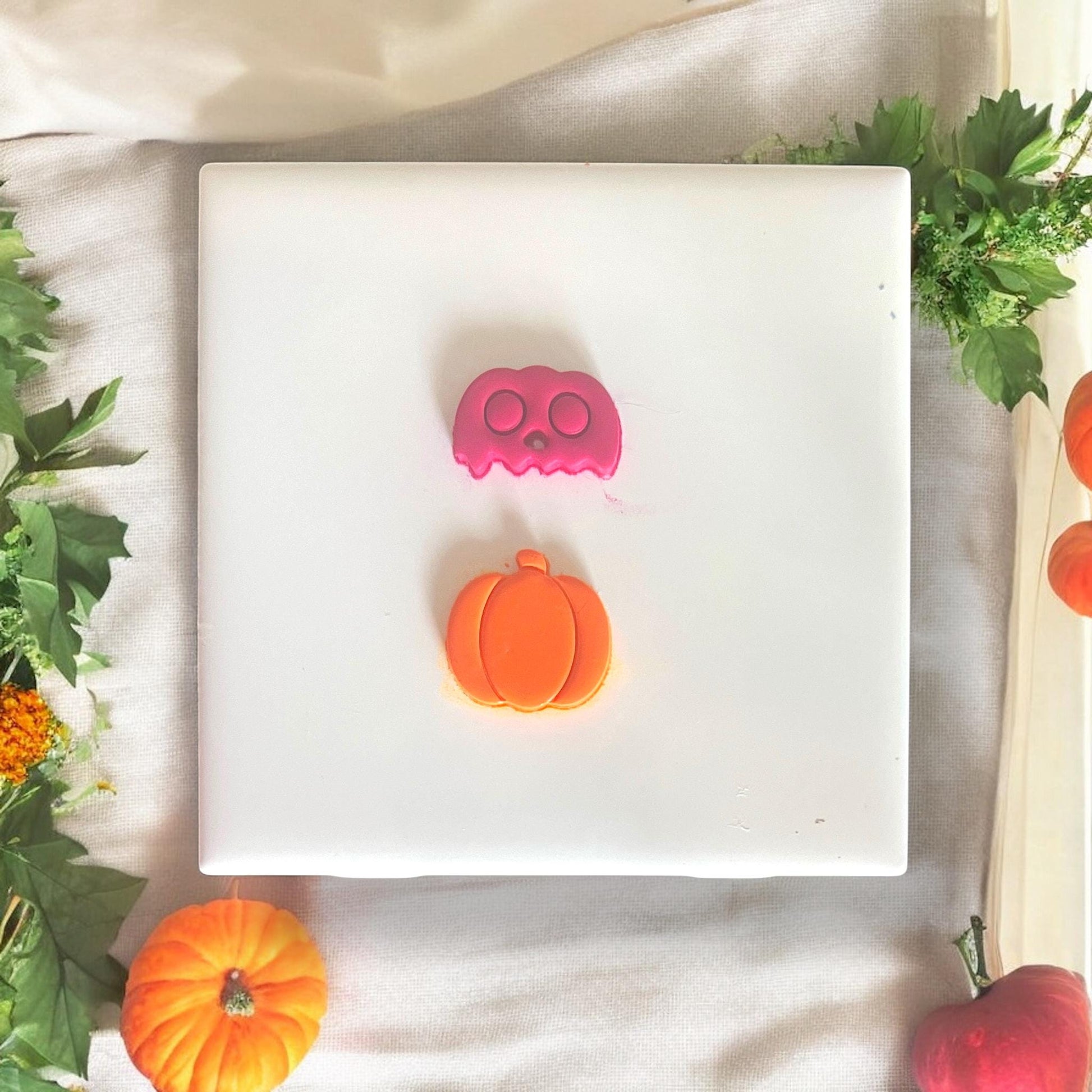 Pink skull and orange pumpkin clay cutouts side by side