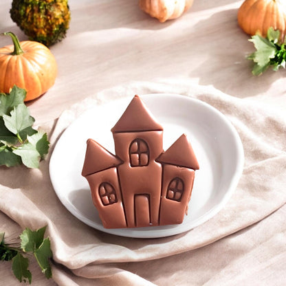 Finished haunted house clay piece on a white plate with pumpkins and leaves