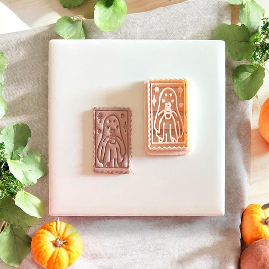 Side-by-side of ghost cutter and its clay impression, styled with mini pumpkins