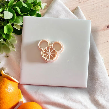 Yellow citrus mouse clay impression centered on white tile