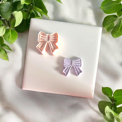 finished girly bow clay dangle next to cutter
