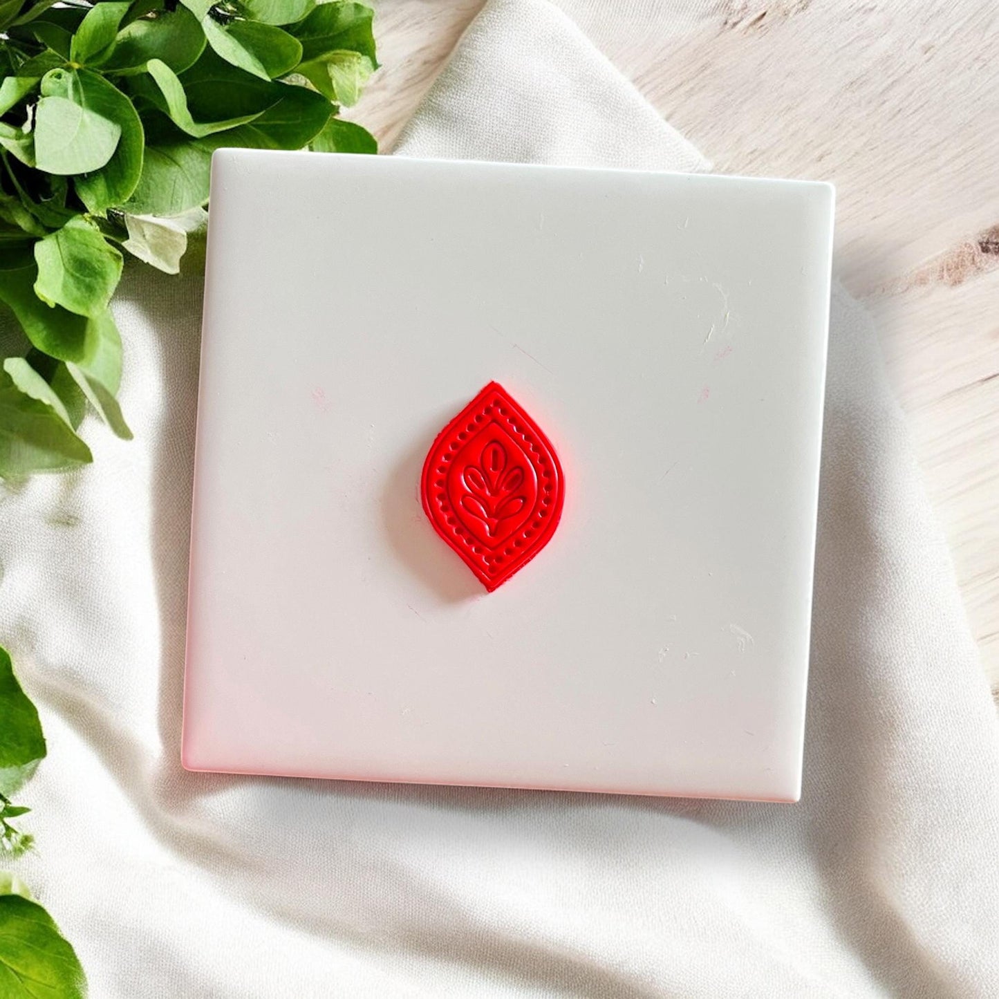 Red polymer clay piece cut in folk leaf petal drop shape