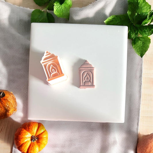 Cutter and finished lantern earring clay piece side by sidePeach-toned polymer clay cutter shaped like a lantern