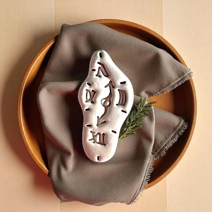 close up of melting clock clay piece on fabric and wooden tray