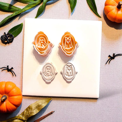 Orange cutters and white clay impressions of ghost couple in decorative frames