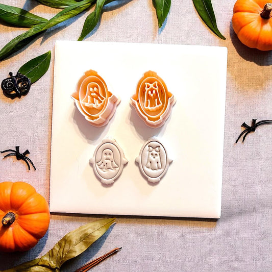 Orange cutters and white clay impressions of ghost couple in decorative frames