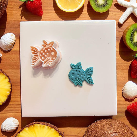 Polymer clay cutter and teal strawberry fish design side by side