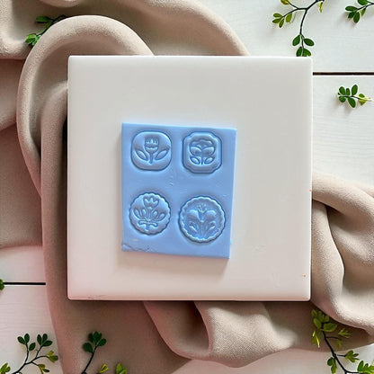 flower charm impressions in raw blue clay, four folk flower designs