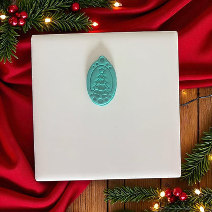 Teal ornament tree cutter displayed on white tile and red holiday fabric