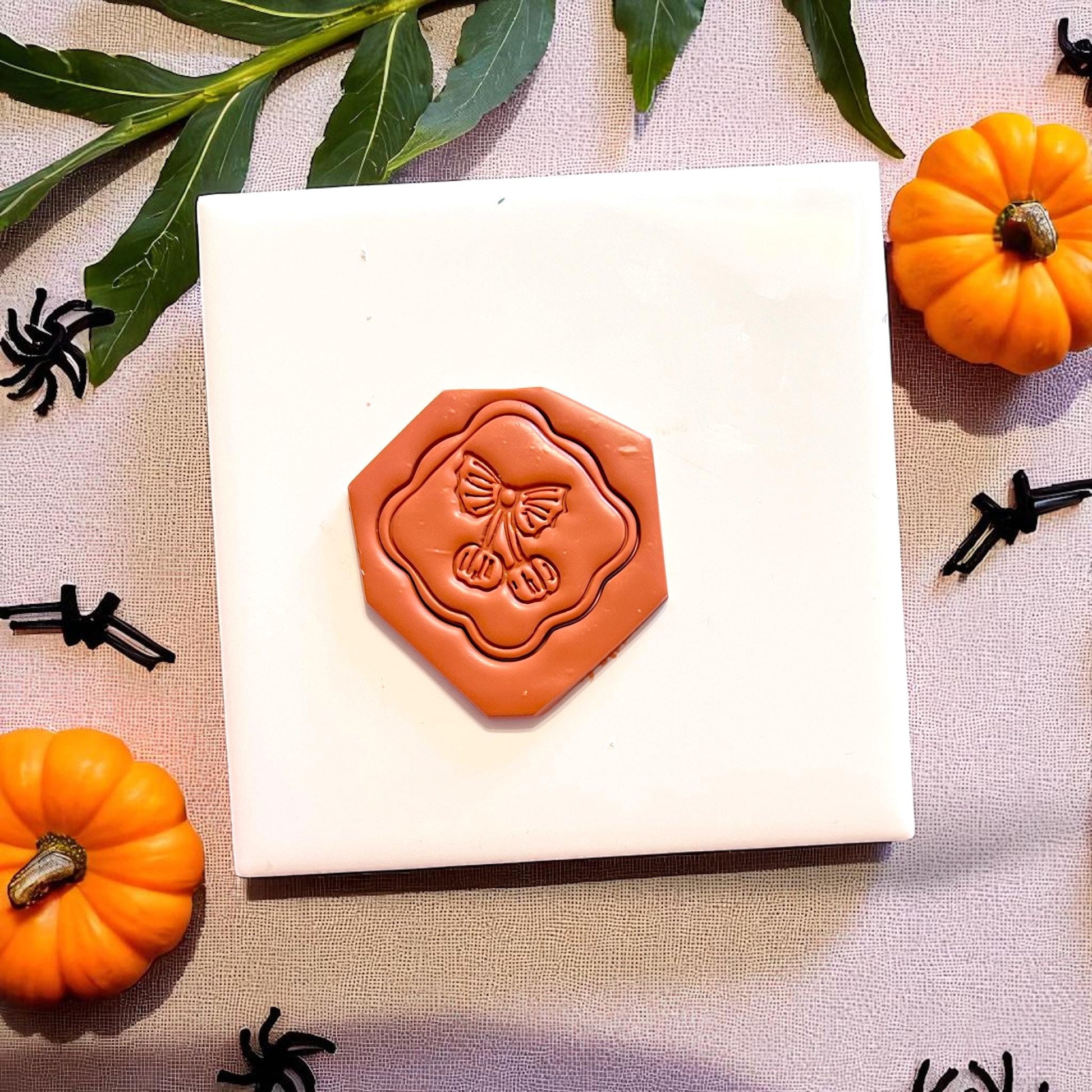 Pumpkin cherry clay imprint on hex tile with fall leaves and spiders