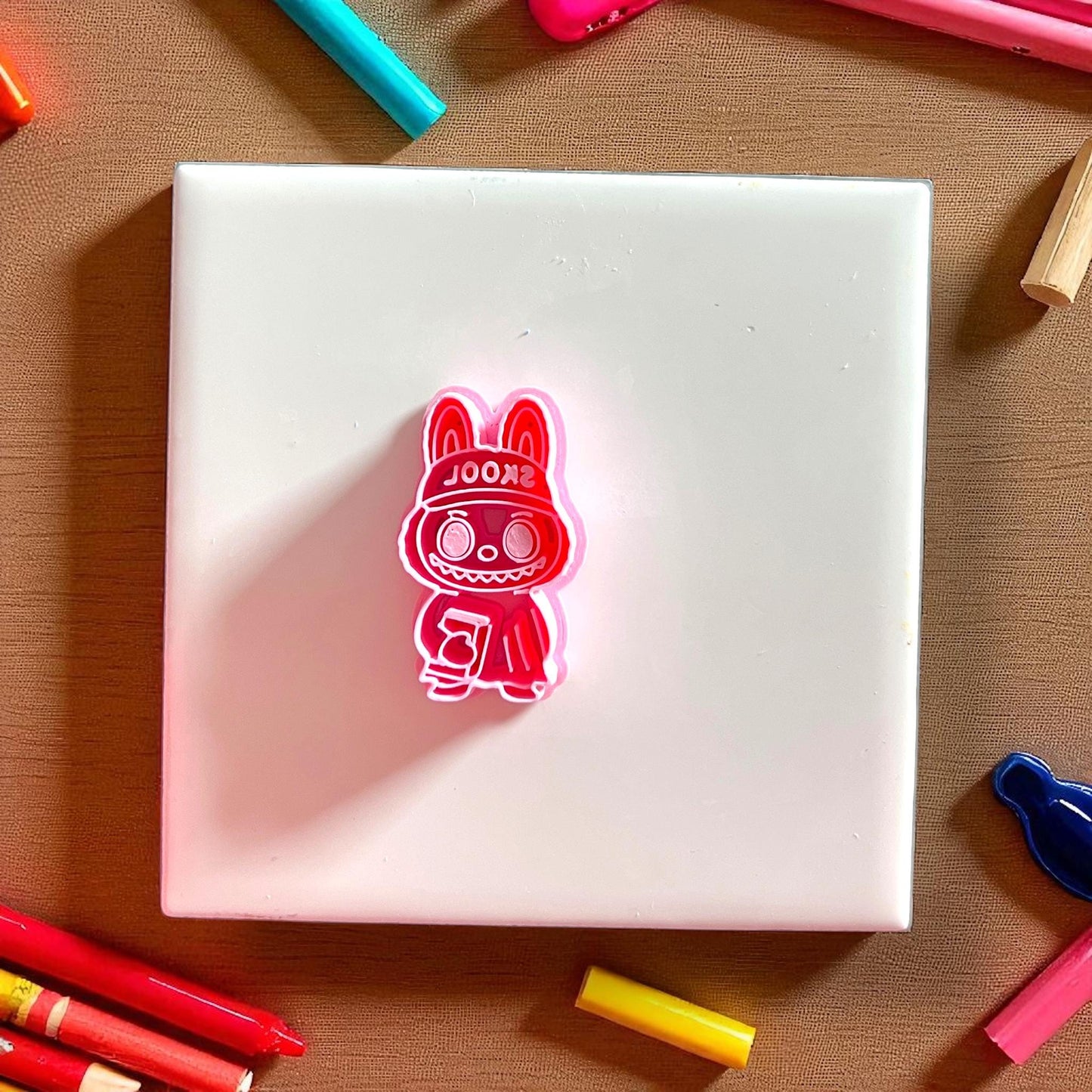 Red school monster cutter holding book on white tile