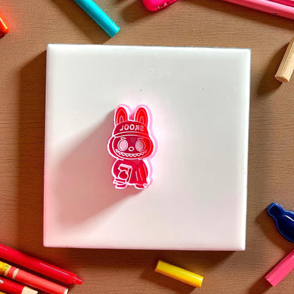 Red school monster cutter holding book on white tile