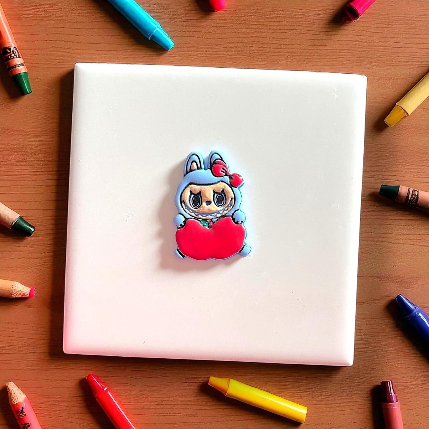 Pink apple holding monster cutter on white tile with tan fabric