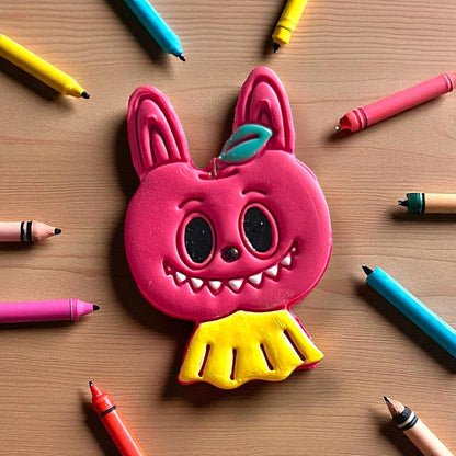 Close-up of detailed apple monster clay piece surrounded by colored pencils