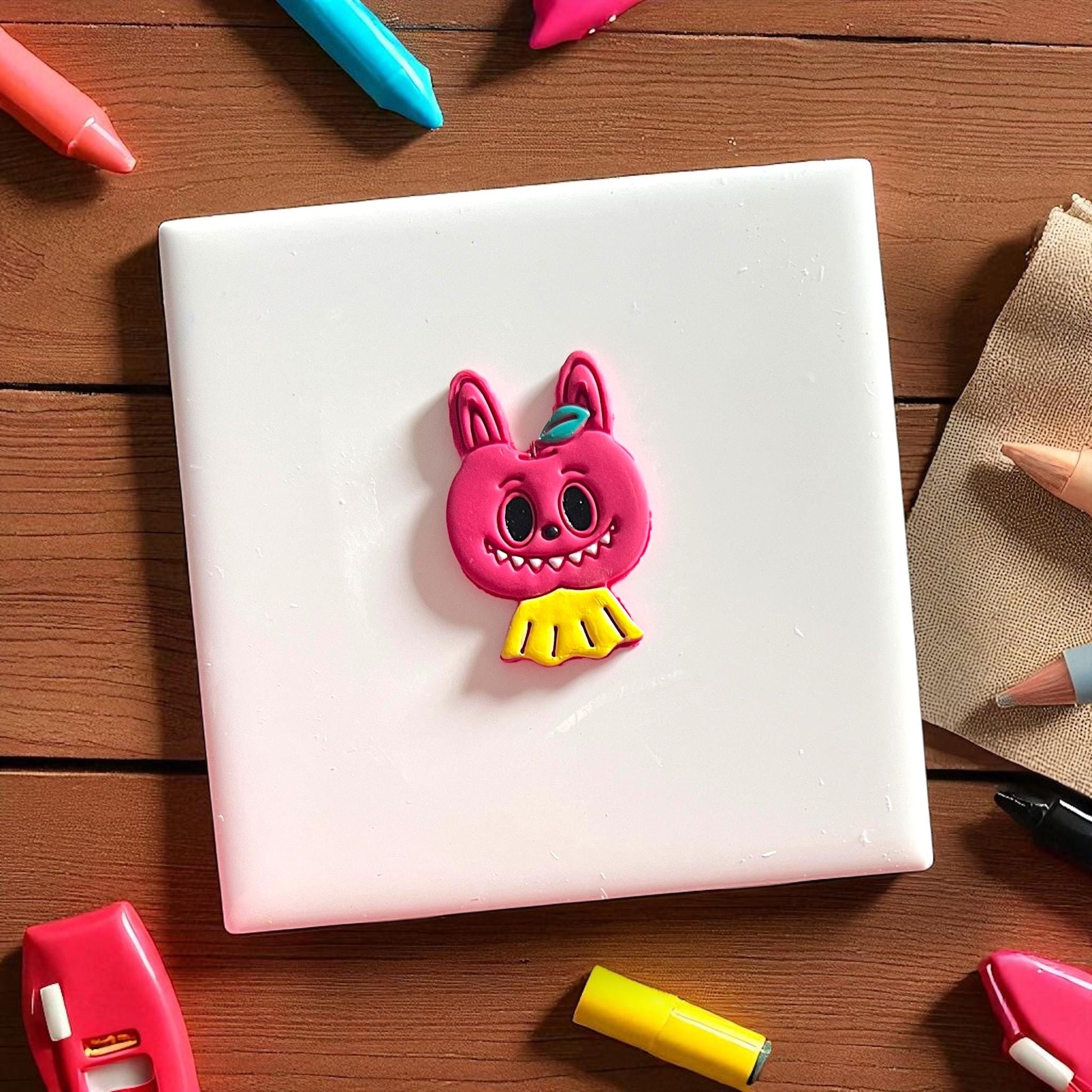 Finished clay piece of scary apple monster with yellow collar and leaf