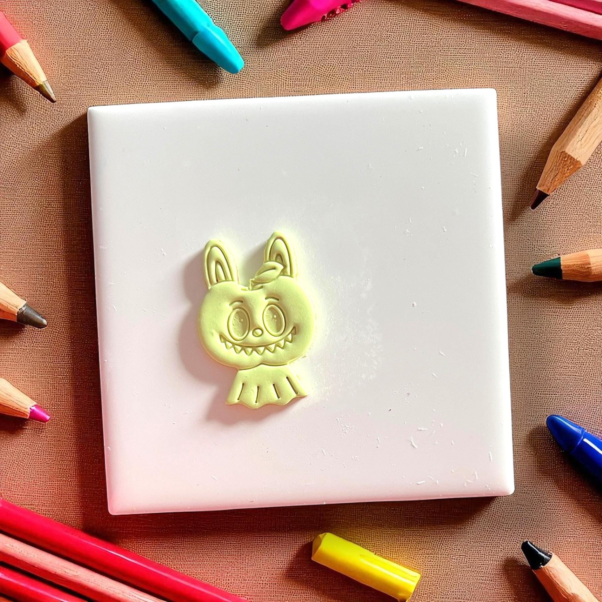 Polymer clay cutout of scary apple monster face with leaf detail