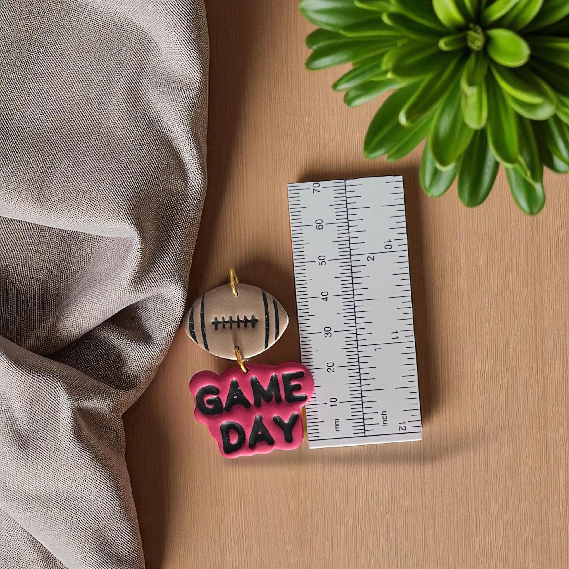 Football Game Day polymer clay earrings shown with ruler for size