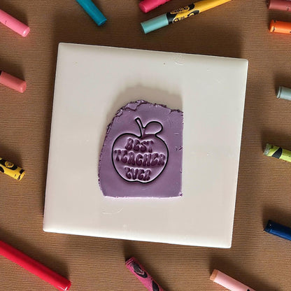 best teacher ever apple clay impression on purple clay sheet surrounded by crayons