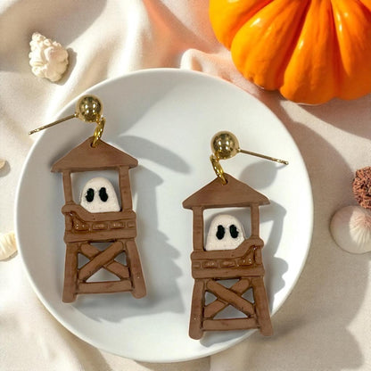 Pair of ghost lifeguard tower earrings with gold posts styled with pumpkin and seashells.