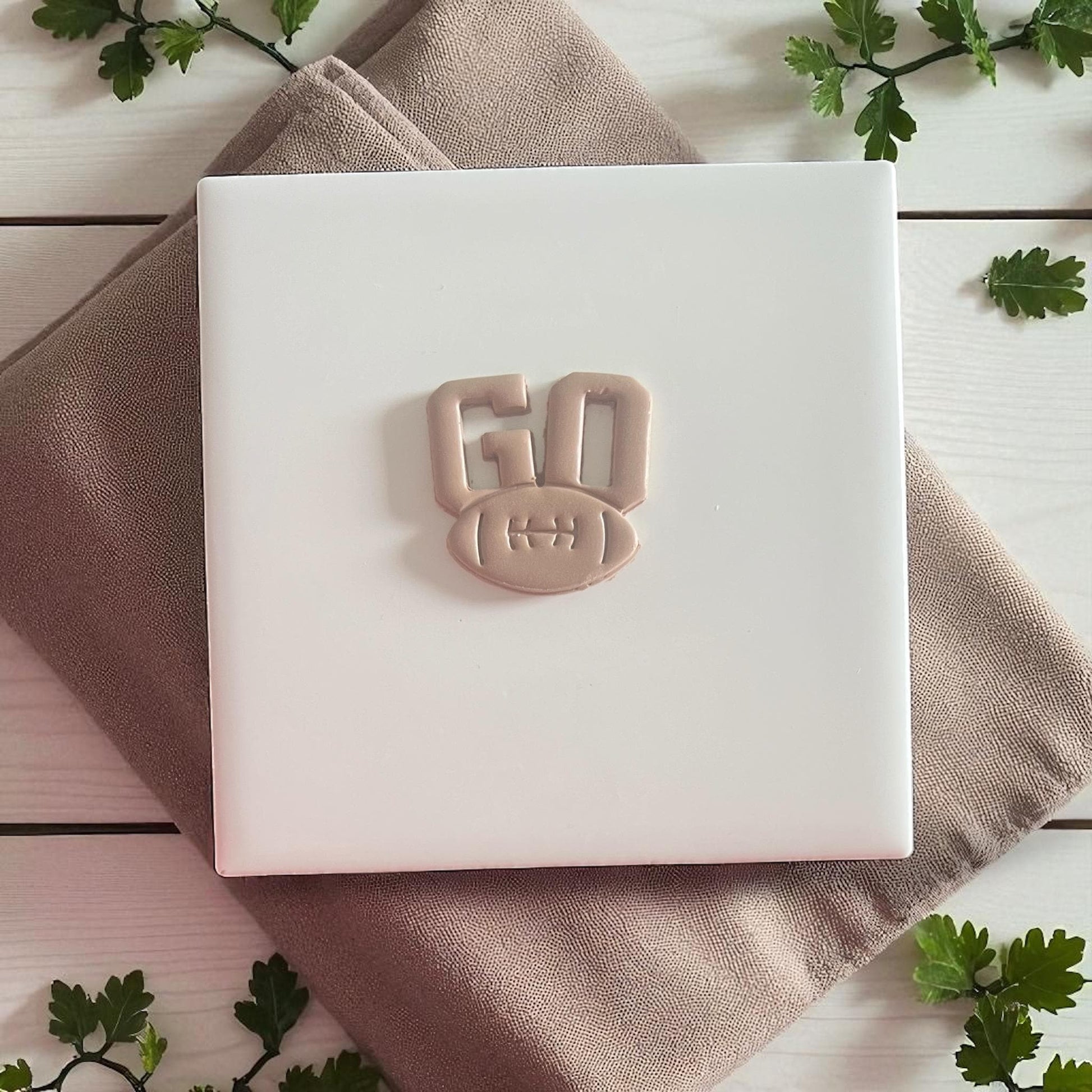 Polymer clay GO football design displayed on neutral square tile