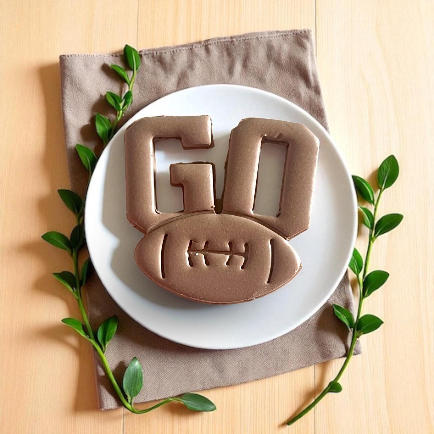 Large GO football earring clay design styled on white plate with greenery