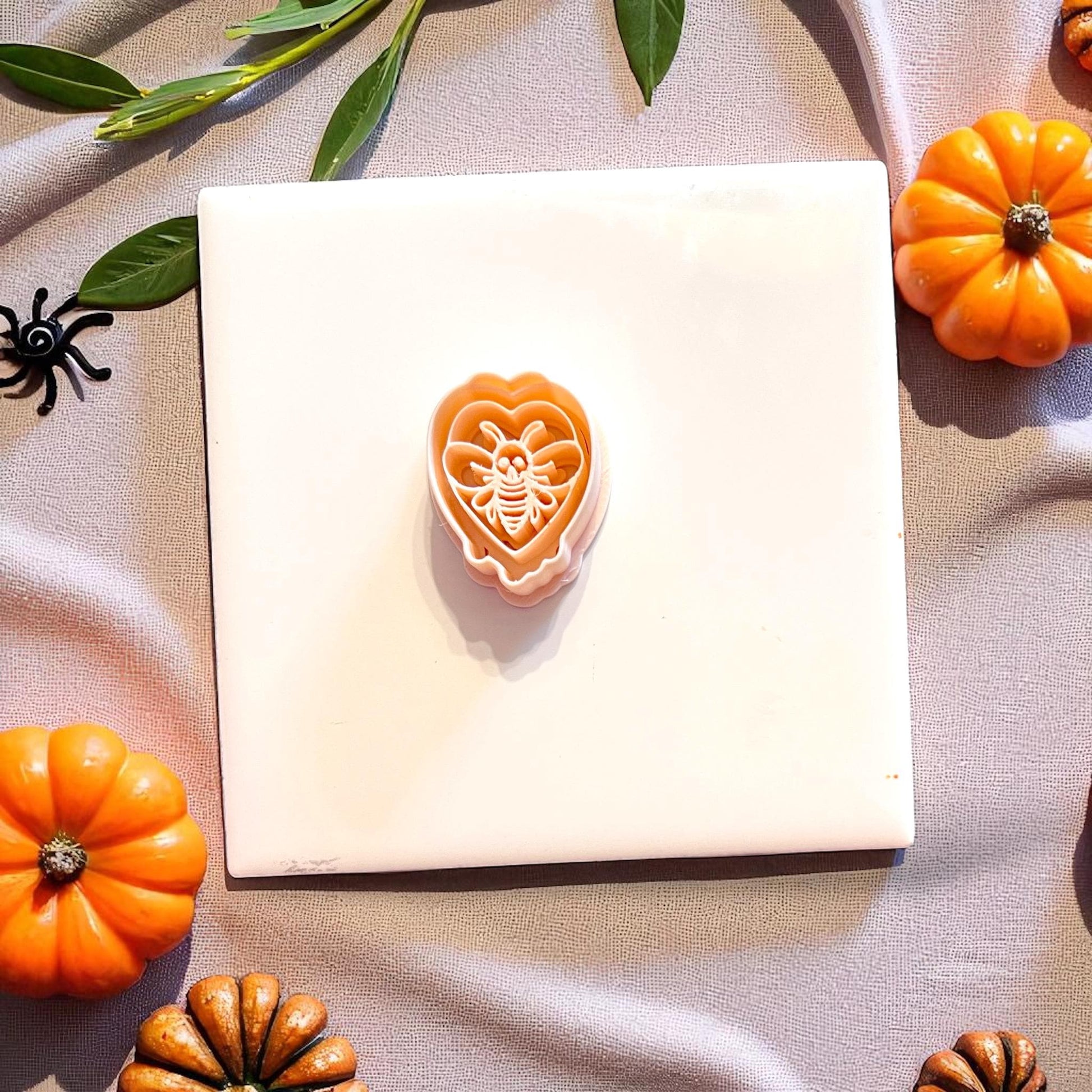 Orange cutter with skeletal moth detail displayed on tile with pumpkins