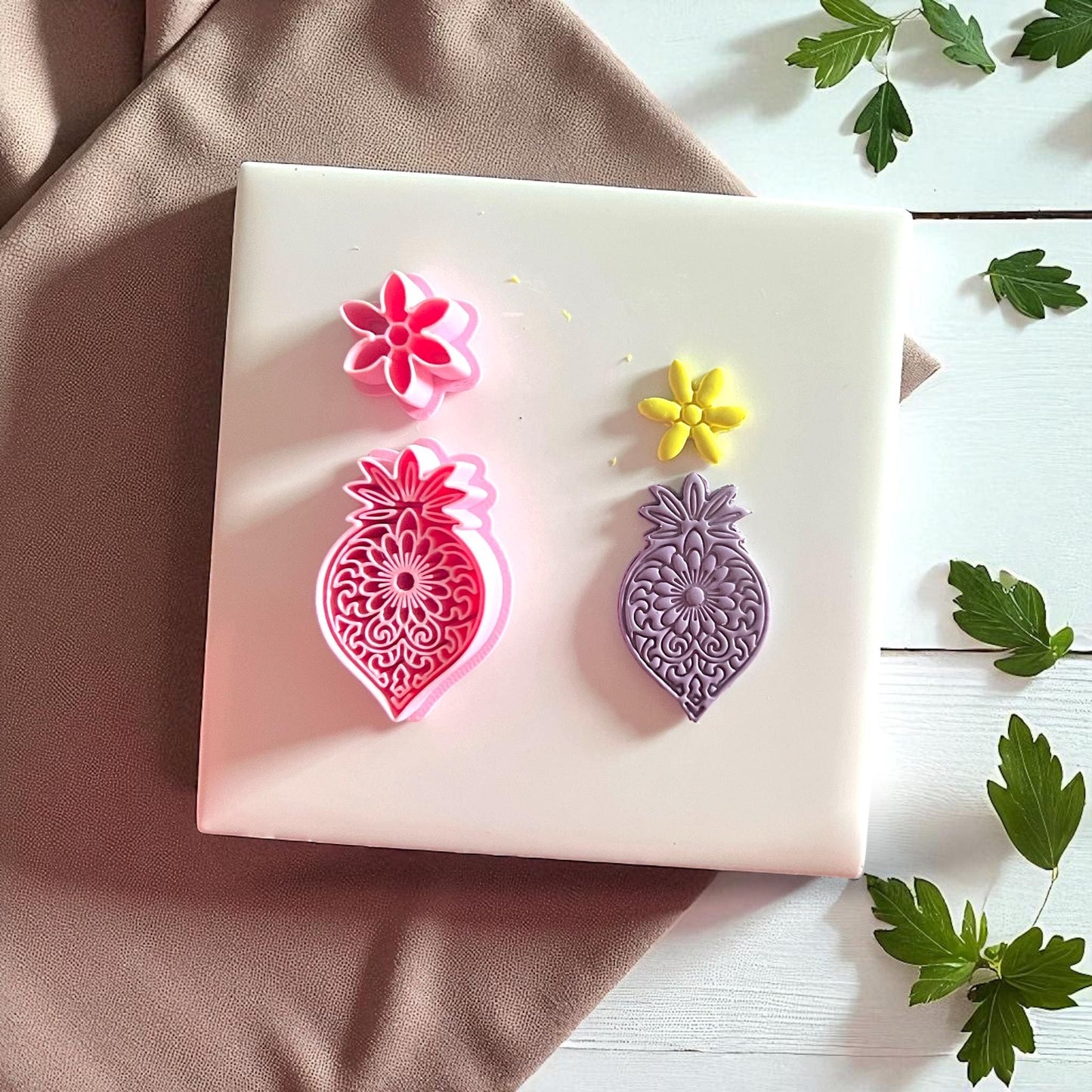 Pink mandala flower cutter with purple clay imprint and yellow flower imprint side by side.
