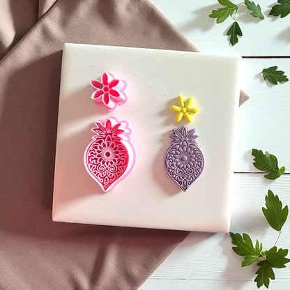 Pink mandala flower cutter with purple clay imprint and yellow flower imprint side by side.