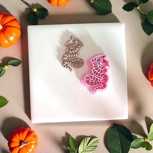 Polymer clay sand serpent next to pink cutter