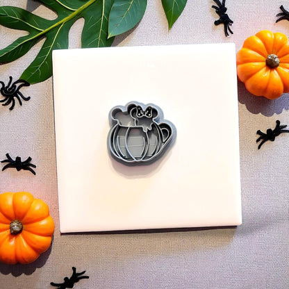 Grey pumpkin mug clay cutter surrounded by pumpkins and Halloween props