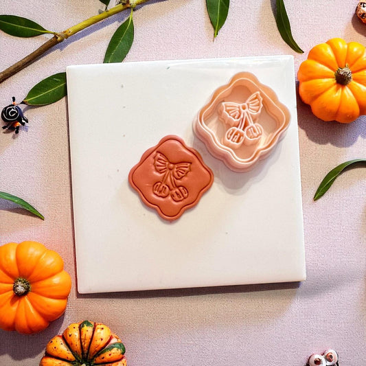 Finished clay piece and matching cutter showing detailed pumpkin cherry impression