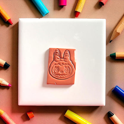 Back to school monster girl clay cutter with bow pressed into orange clay