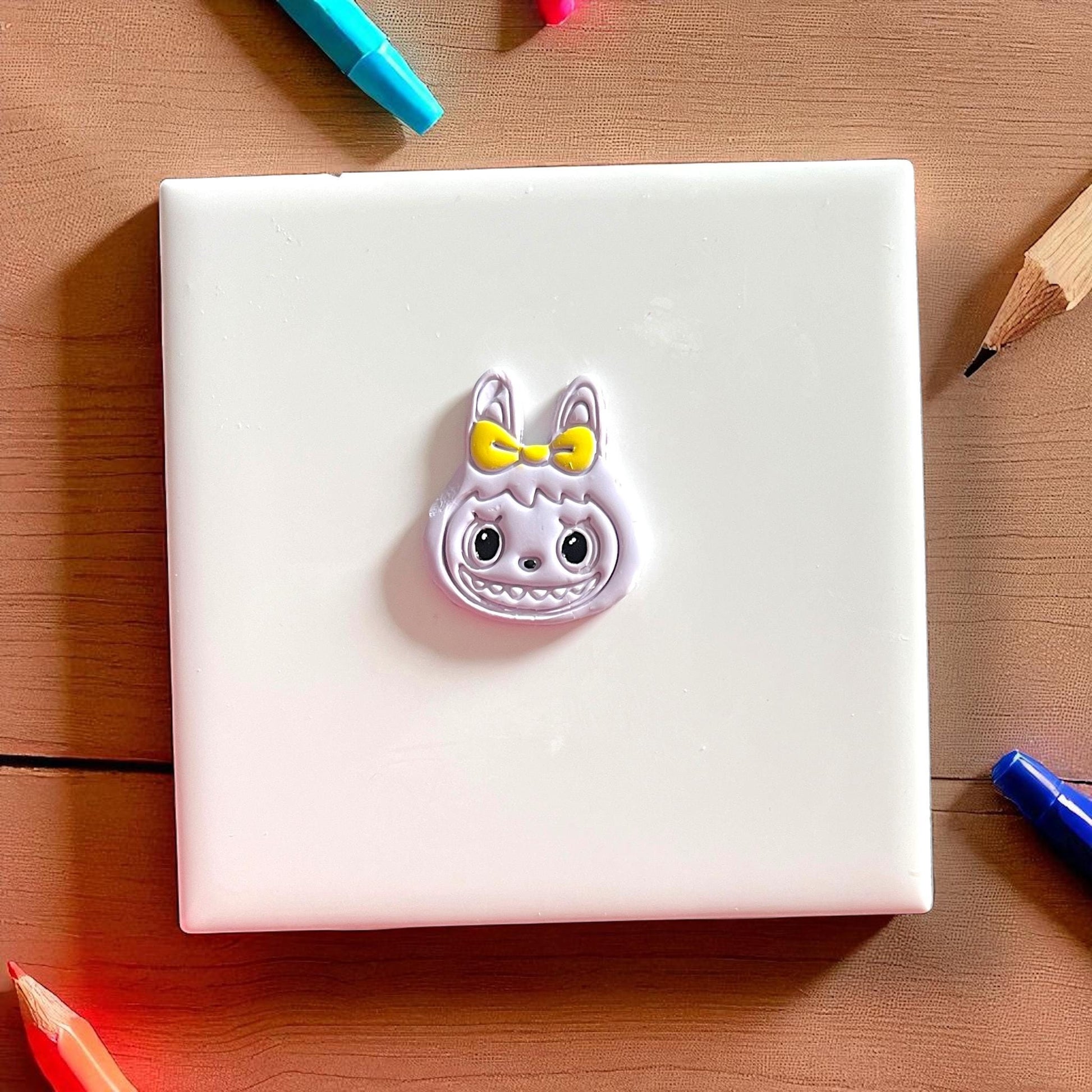 Large monster girl head charm with yellow bow and wide smile