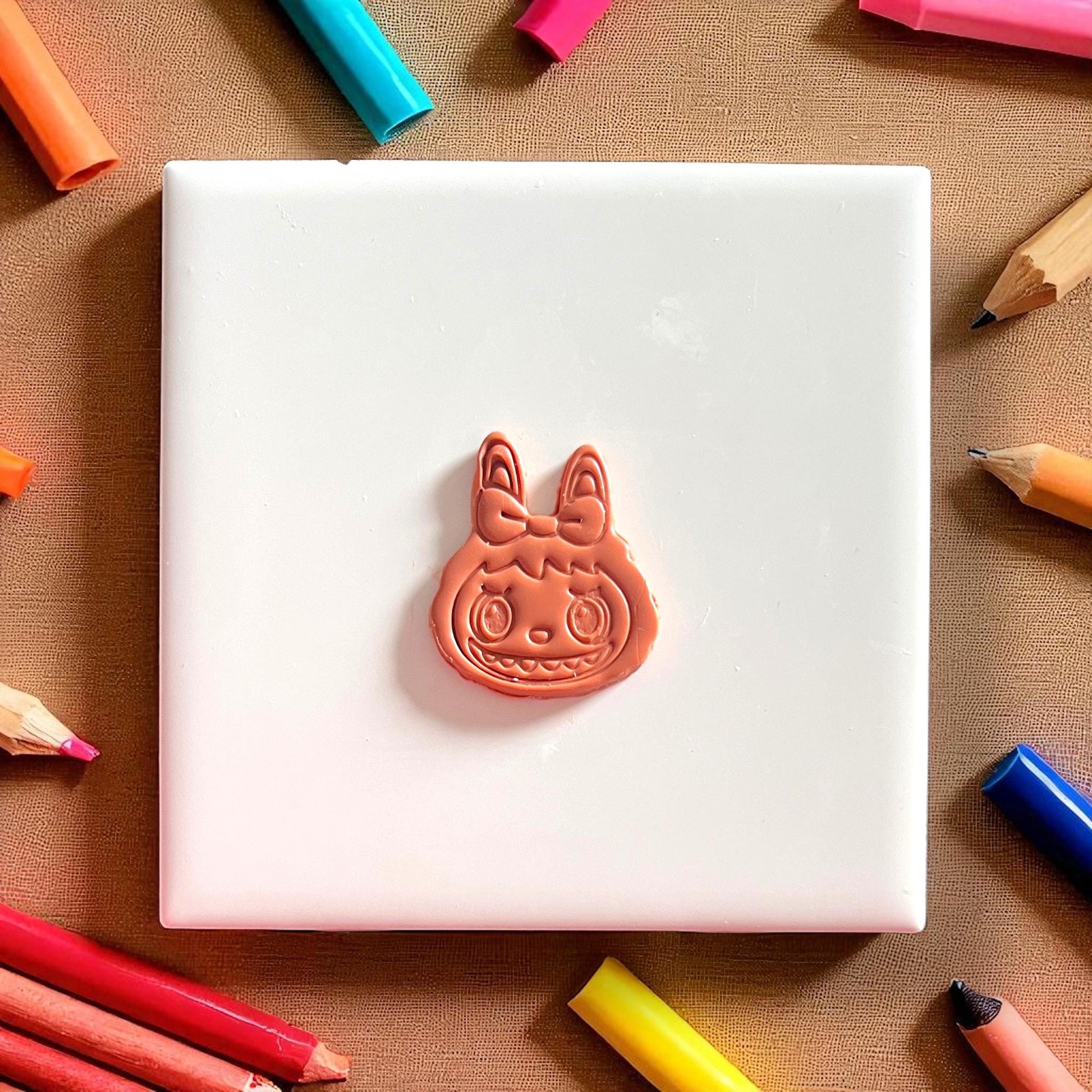 Monster girl face with bow cut from orange polymer clay