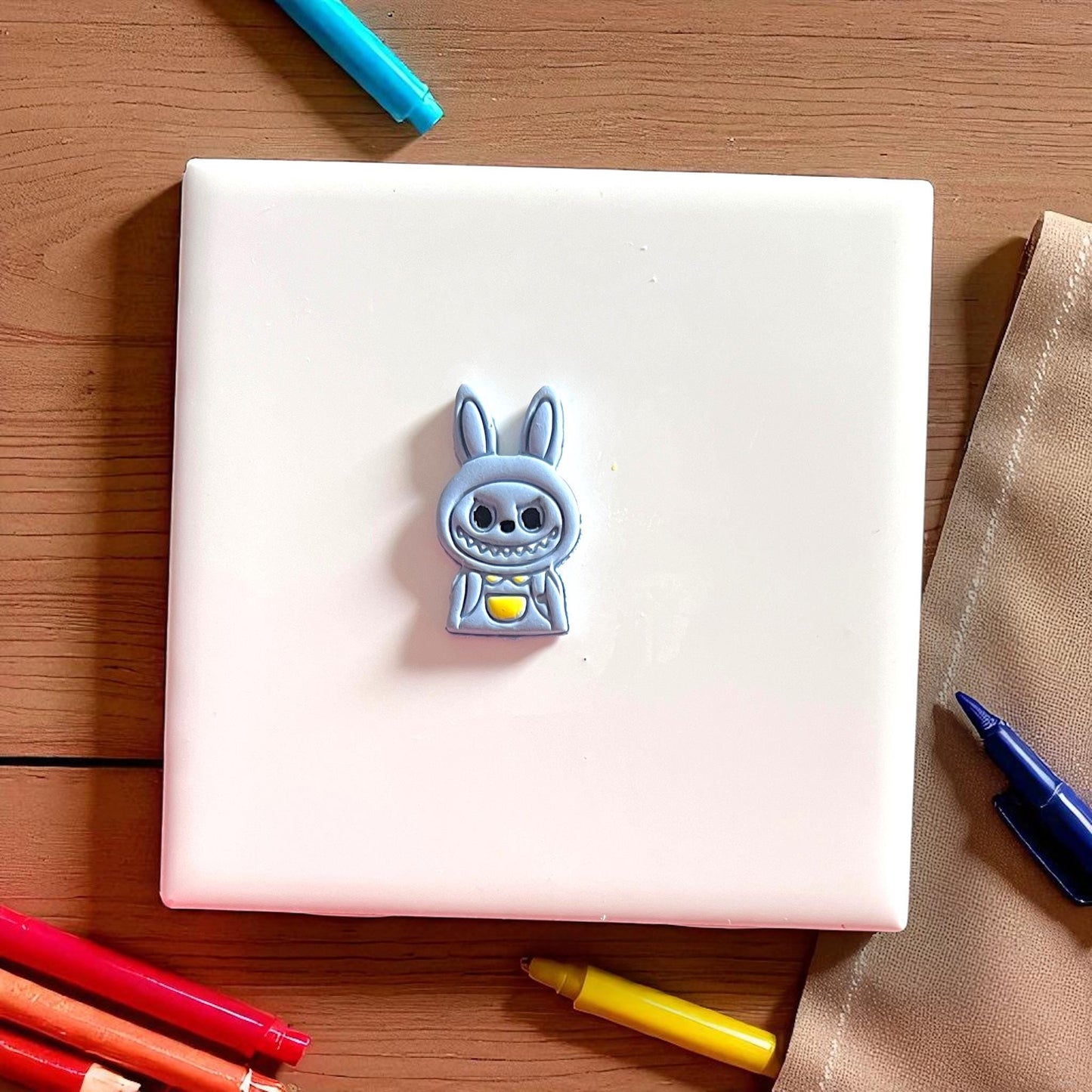 Pink polymer clay cutter in monster boy shape placed on white tile