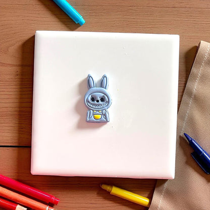 Pink polymer clay cutter in monster boy shape placed on white tile