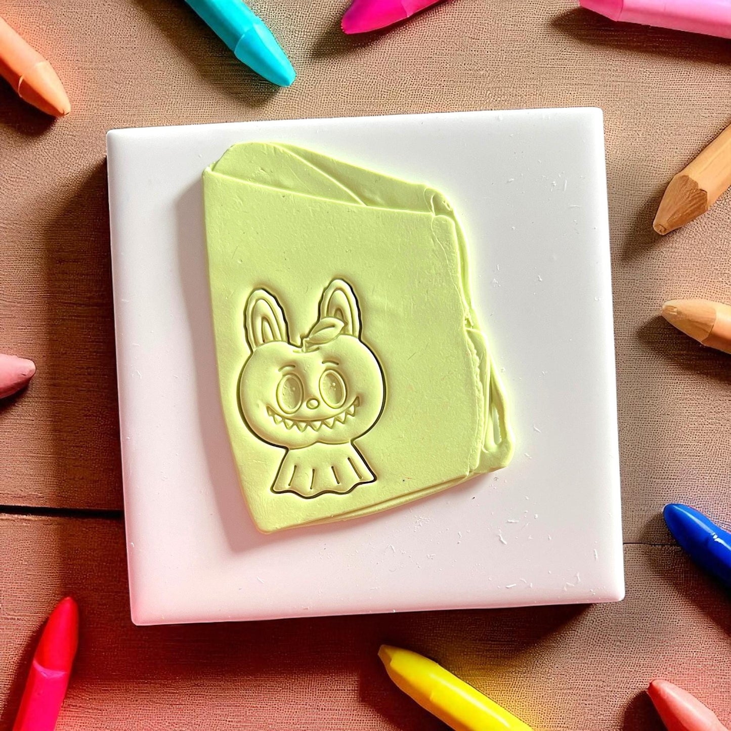 Clay impression of scary apple monster character on green clay