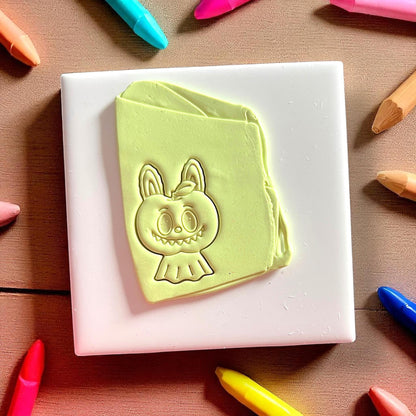 Clay impression of scary apple monster character on green clay